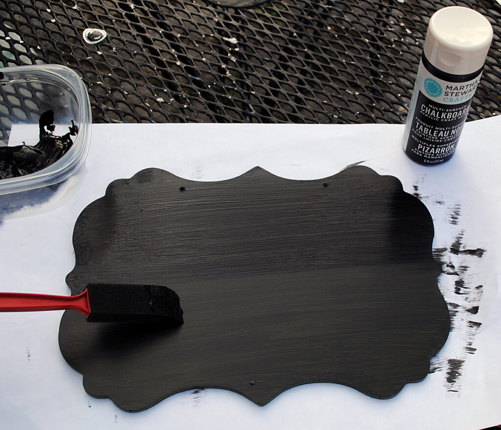 Painting the chalkboard sign with a foam brush and chalkboard paint