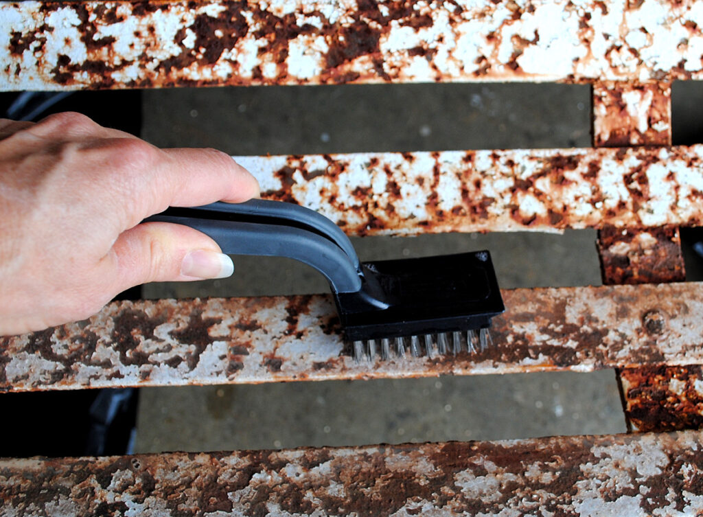 Using wire brush on rusty metal bench