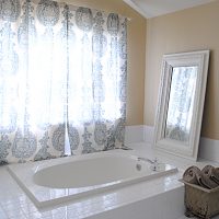 Master bath reveal with tub and mirror and blue curtains