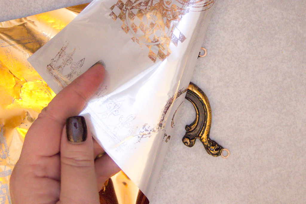 peeling back foil to reveal gold jewelry piece