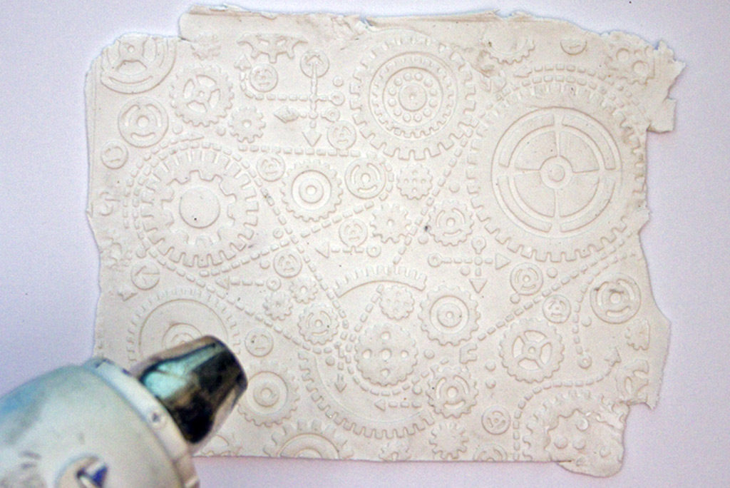 white clay with embossed gear design and heat tool