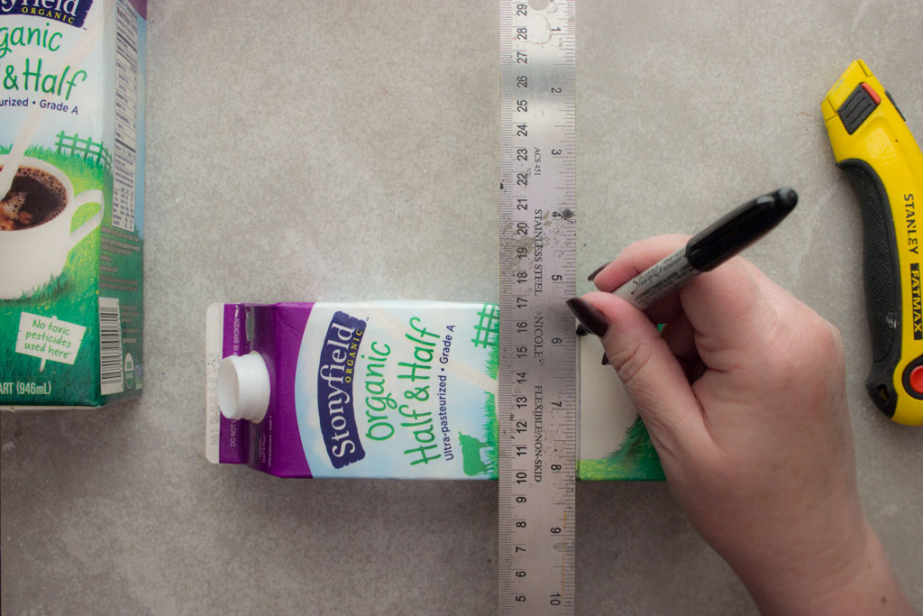 marking milk carton with ruler and knife