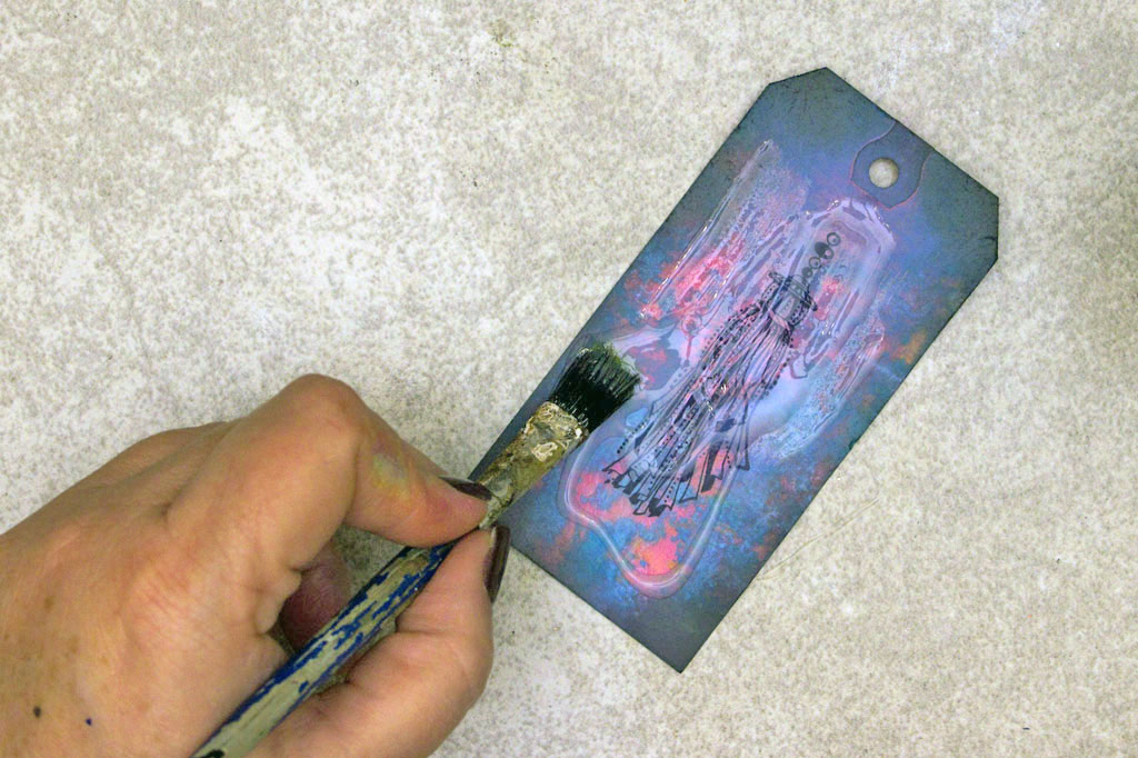 applying glaze to tag with brush