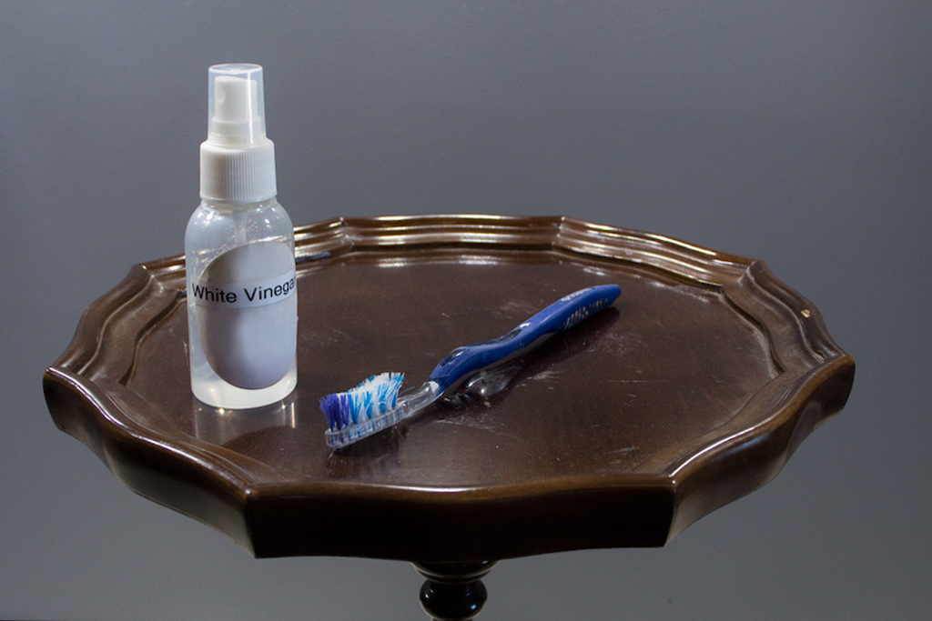 vinegar and toothbrush on wooden table