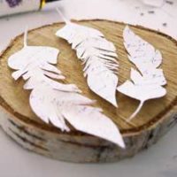 Paper feathers on wood tree section