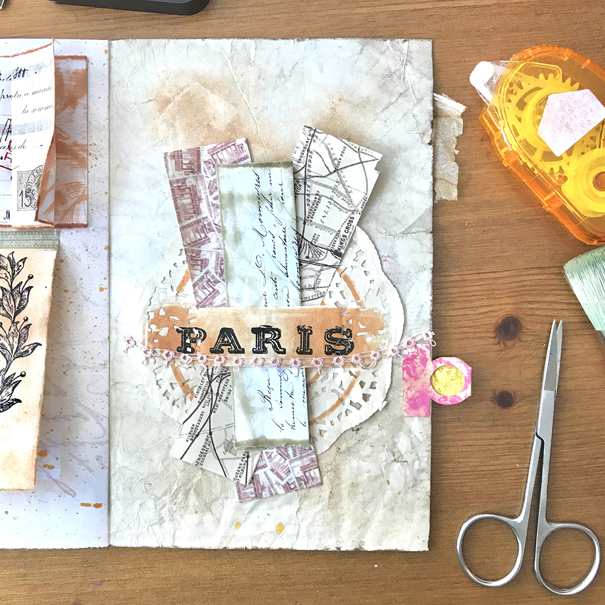 Paris with doily and papers on page and scissors and tape