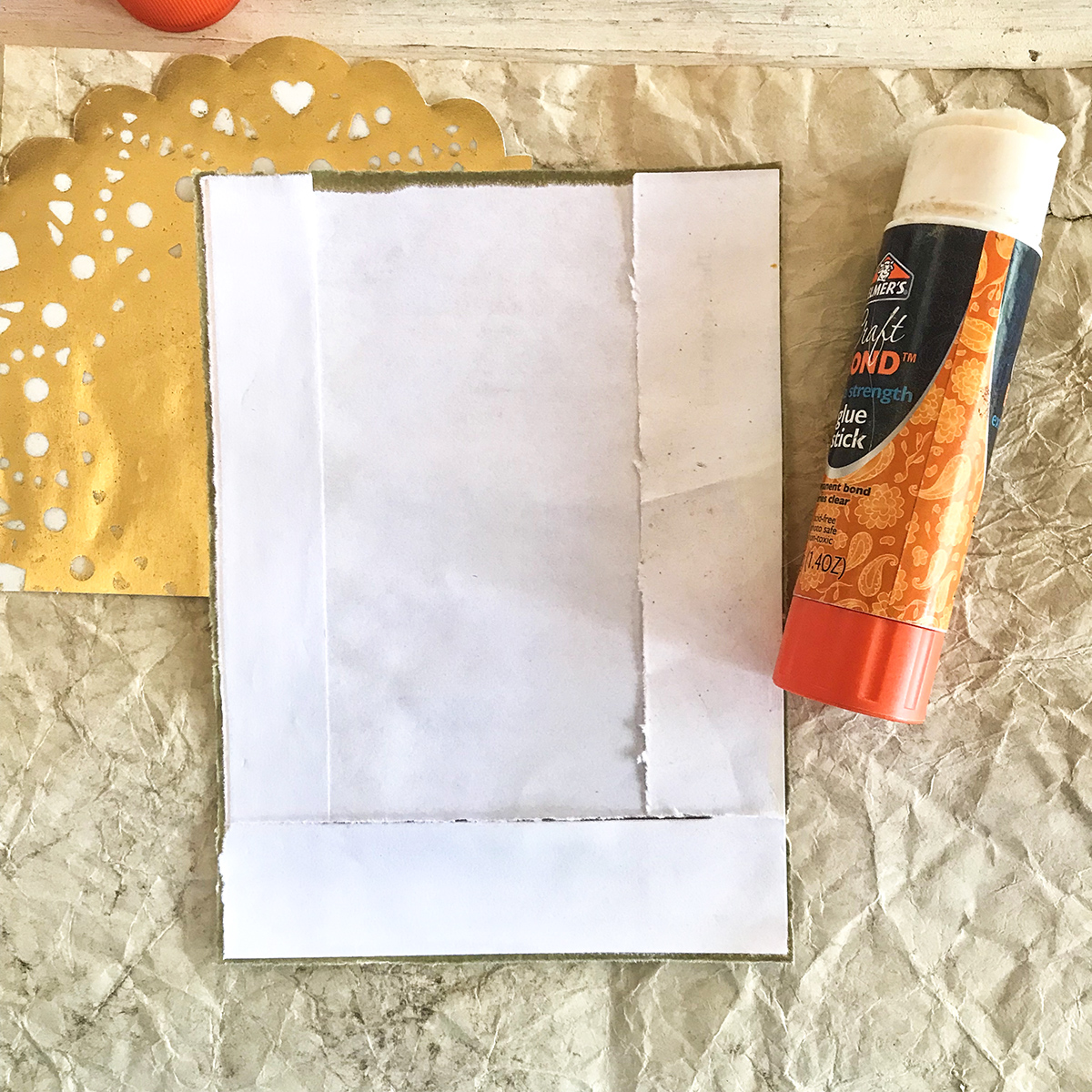 folding paper with gold doily and glue stick