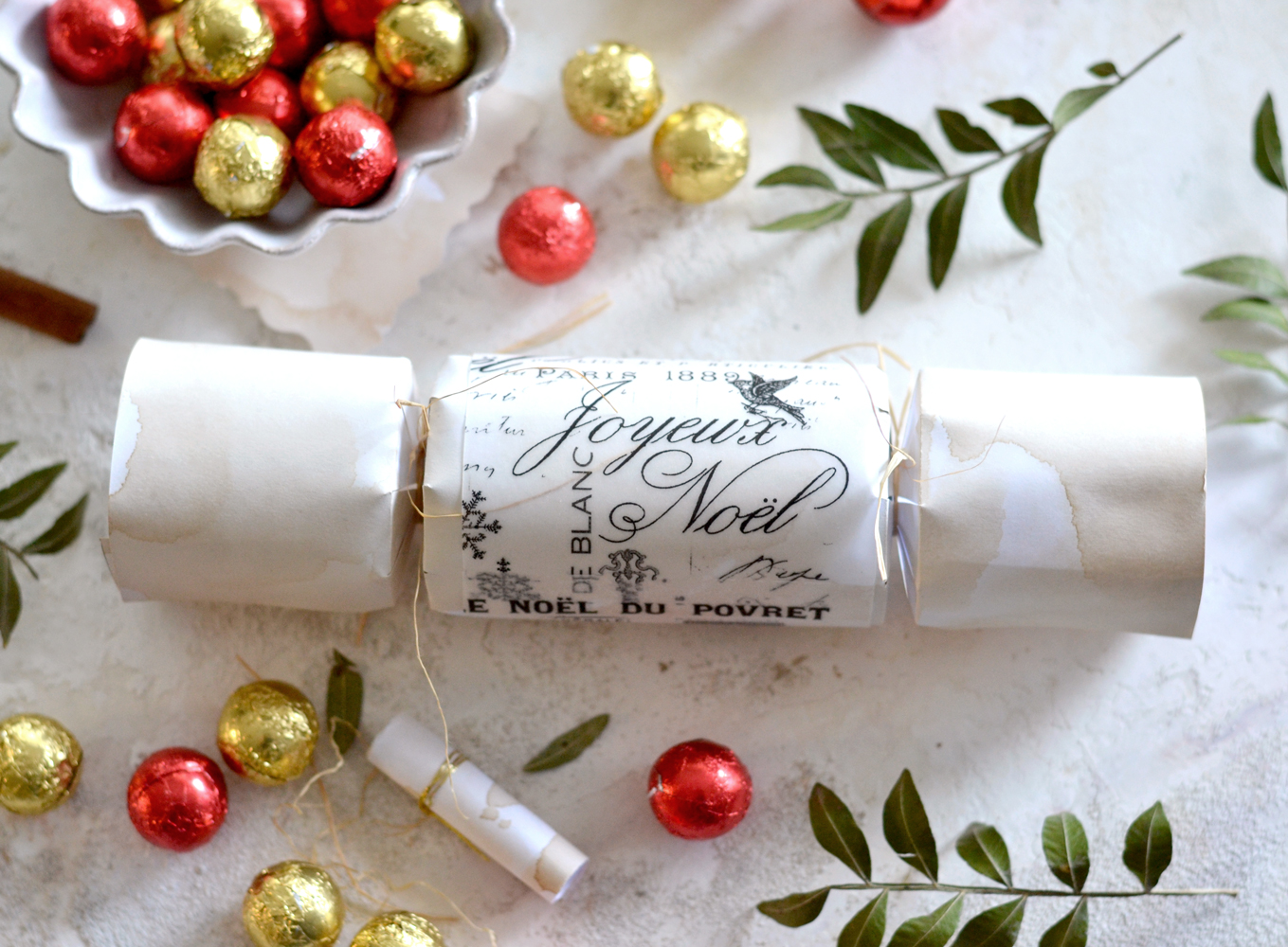 One 'Joyeux Noel' Christmas paper cracker placed on a table along with other seasonal elements