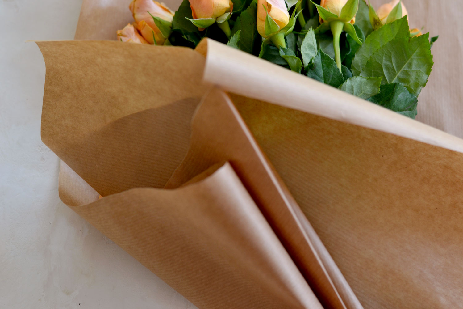 Hands of Caucasian woman wrapping bouquet in brown paper Stock