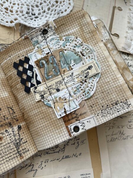 Collaged journal page with black and white ephemera and doily